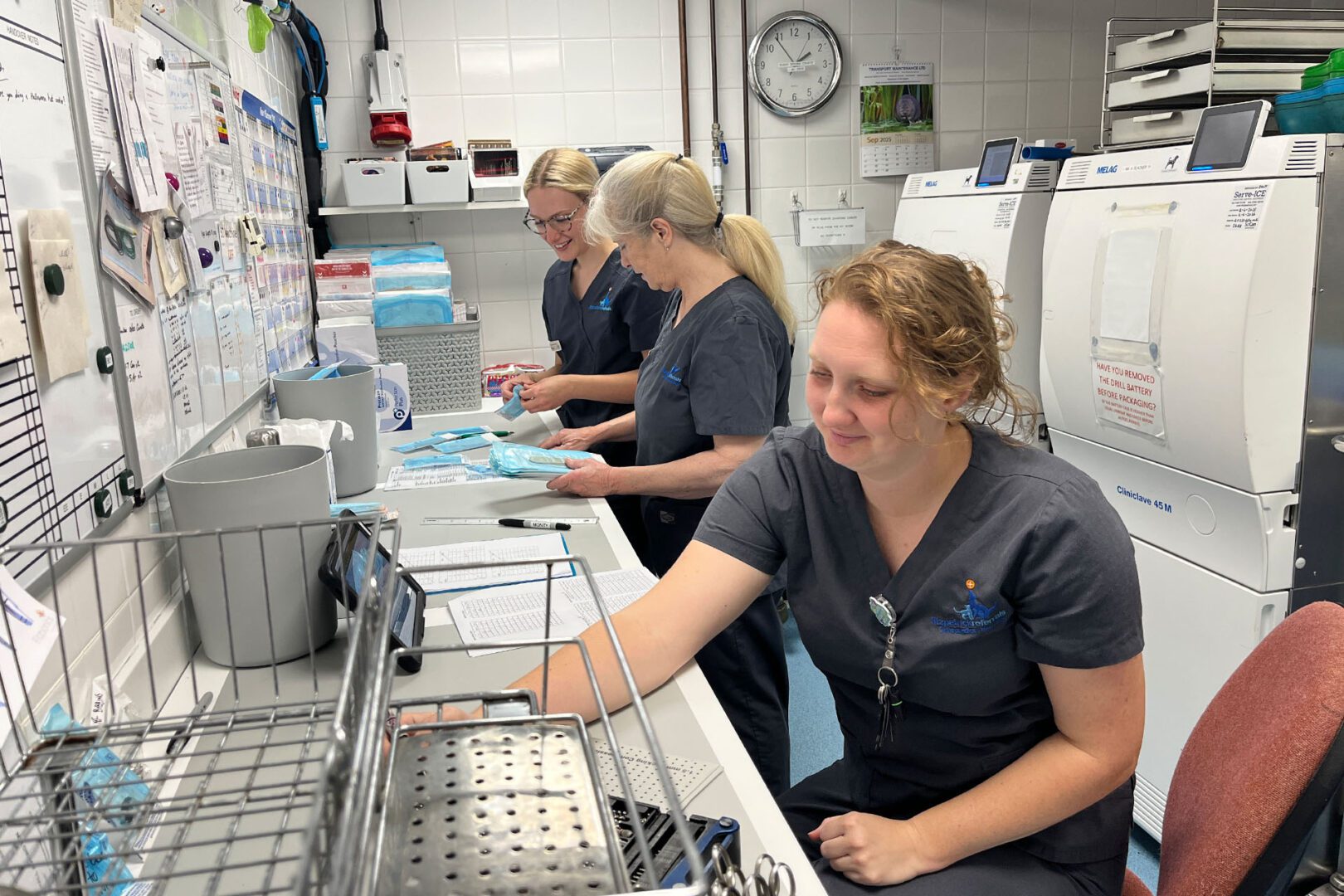 Three veterinary surgical technicians preparing kit for surgeries